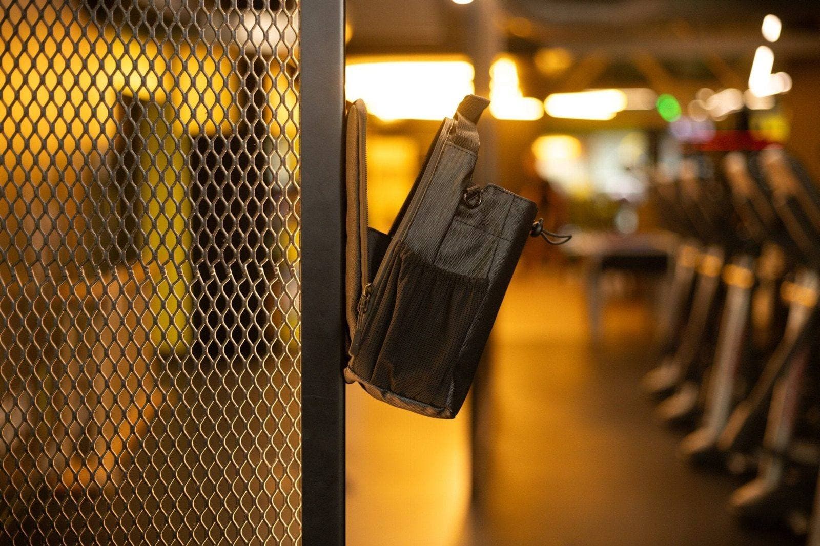 HoldIt magnetic gym bag in orange on a weight bench in a modern gym